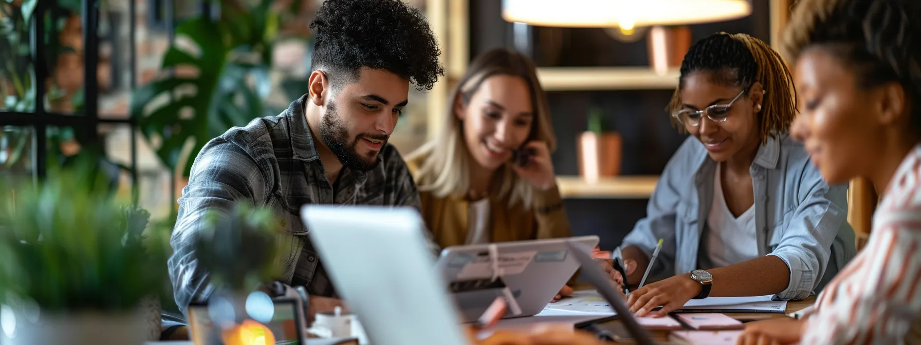 Professionals work together at a desk with digital devices, demonstrating the productivity benefits of a top proposal software program for managing proposals seamlessly.